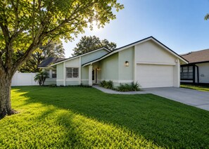 A single-story house with a garage, a well-maintained lawn, and a tree in the foreground. - Orlando Hub: Cozy Suburban Oasis / 25 Mins to Theme Parks  &Airport (Orlando)