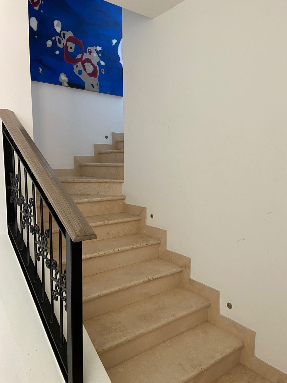 Eine Treppe mit beigen Stufen und einem schwarzen Geländer.