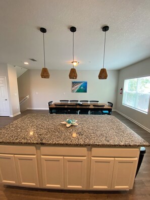 A kitchen with a granite countertop, white cabinets, and pendant lights. - Jax Beach Vacation Stay, 4 bathrooms, 5-bedroom, 2 fire pits, and 2 balconies (Jacksonville Beach)
