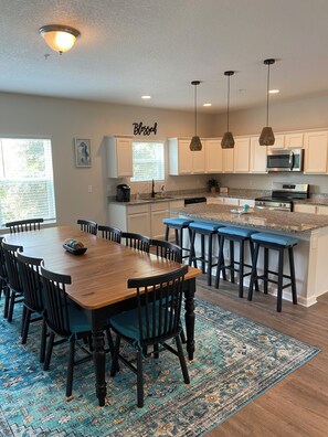 Una cocina moderna con una mesa de comedor de madera, taburetes de bar y un tapete estampado.