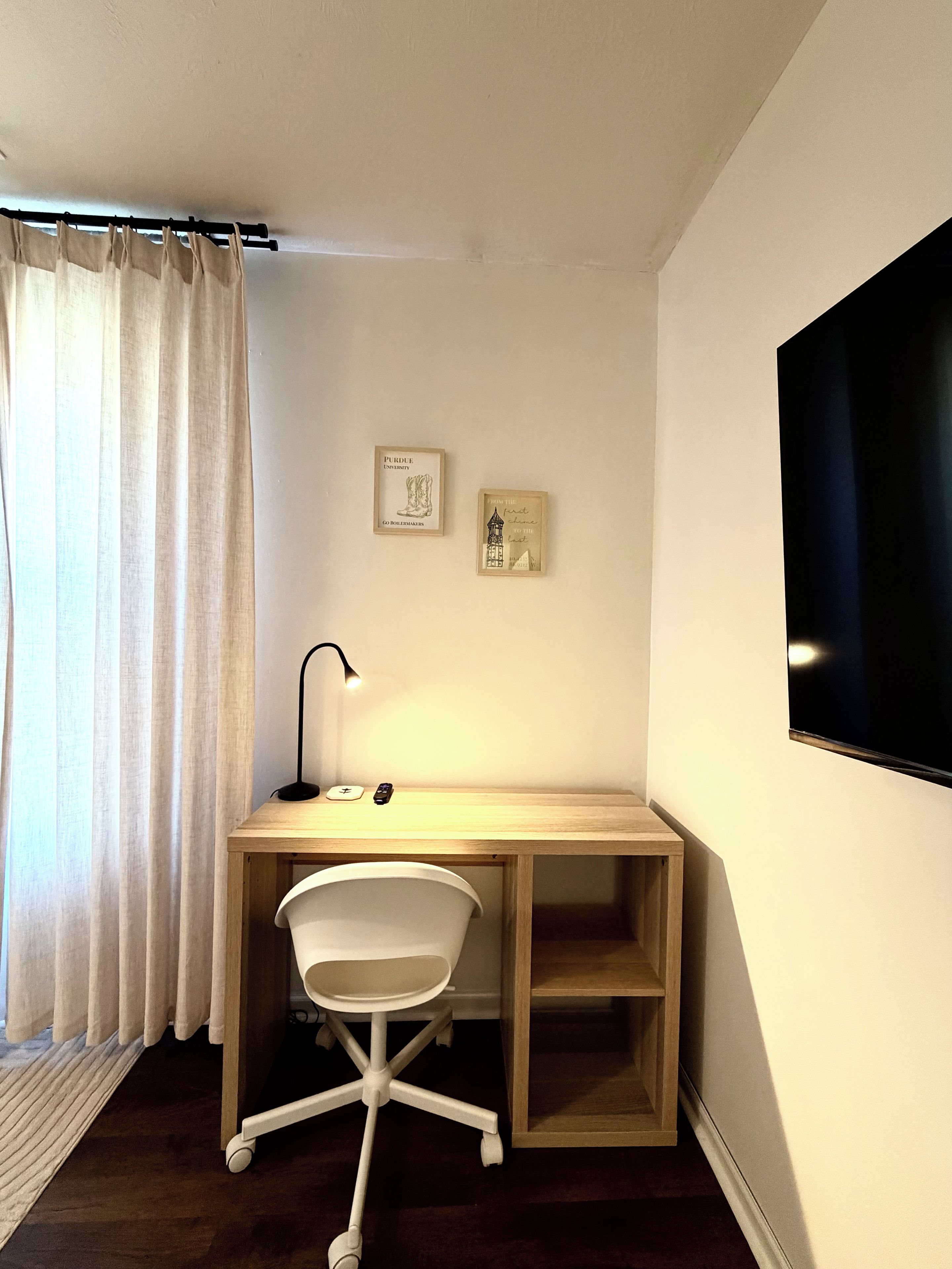 Ett litet, välordnat kontorsutrymme med ett skrivbord, en stol och två inramade tavlor på väggen.