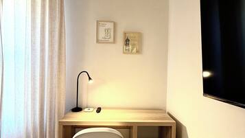 Ett litet, välordnat kontorsutrymme med ett skrivbord, en stol och två inramade tavlor på väggen.
