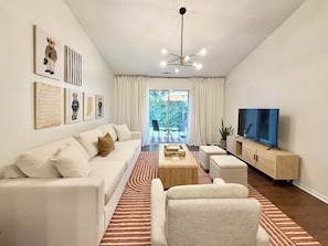 Una sala de estar moderna con un sofá, una mesa de centro, un televisor y obras de arte en las paredes.