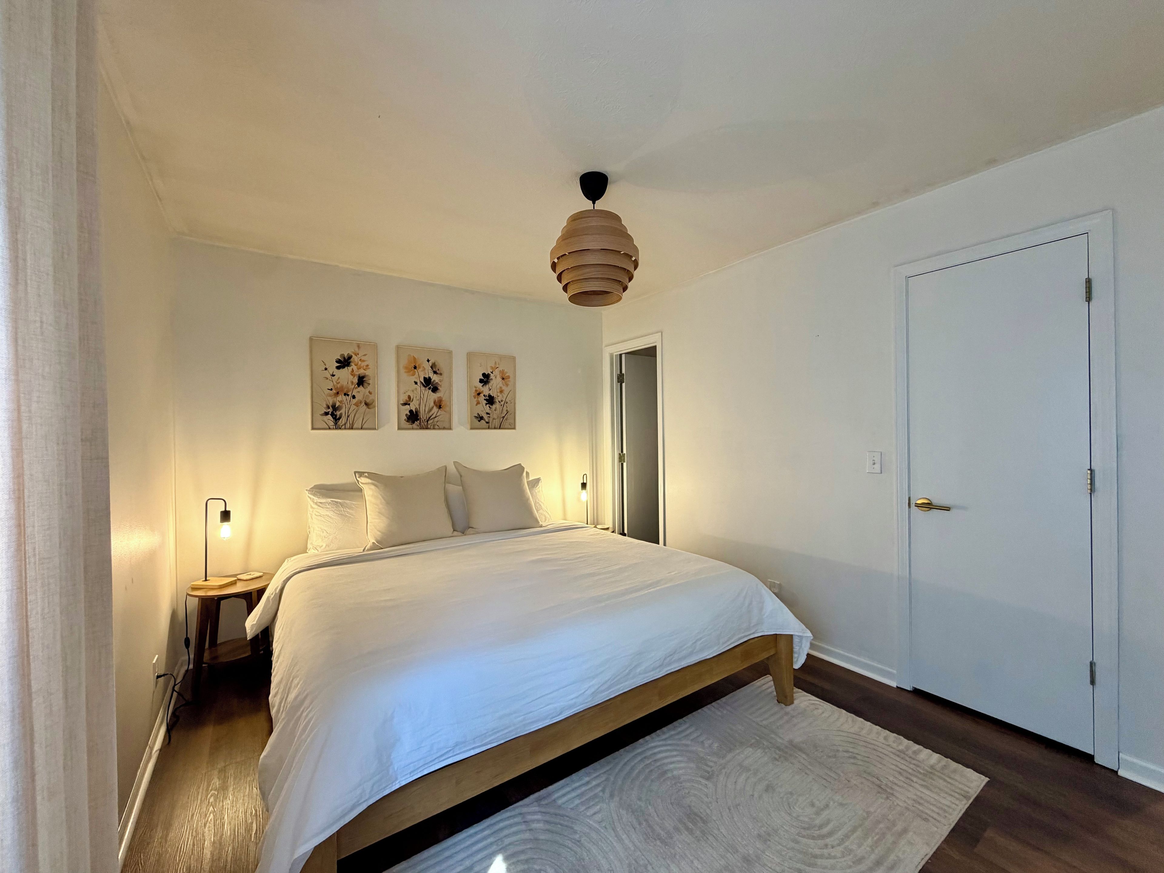 Un dormitorio con cama, lámparas de noche, ventilador de techo y una puerta.