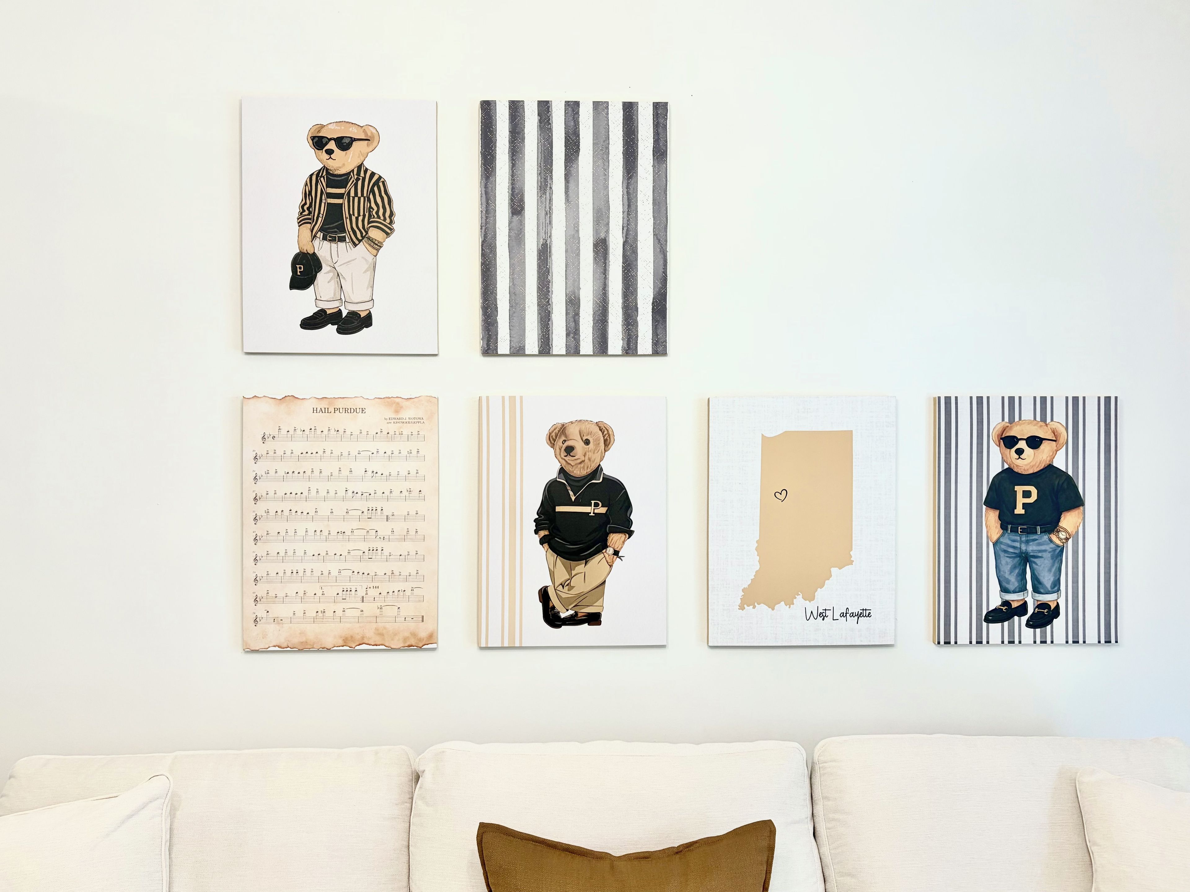 A wall with four framed artworks, a couch with cushions, and a partial view of a room.