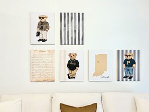 Un mur orné de quatre œuvres d’art encadrées, un canapé avec des coussins et une vue partielle d’une pièce.