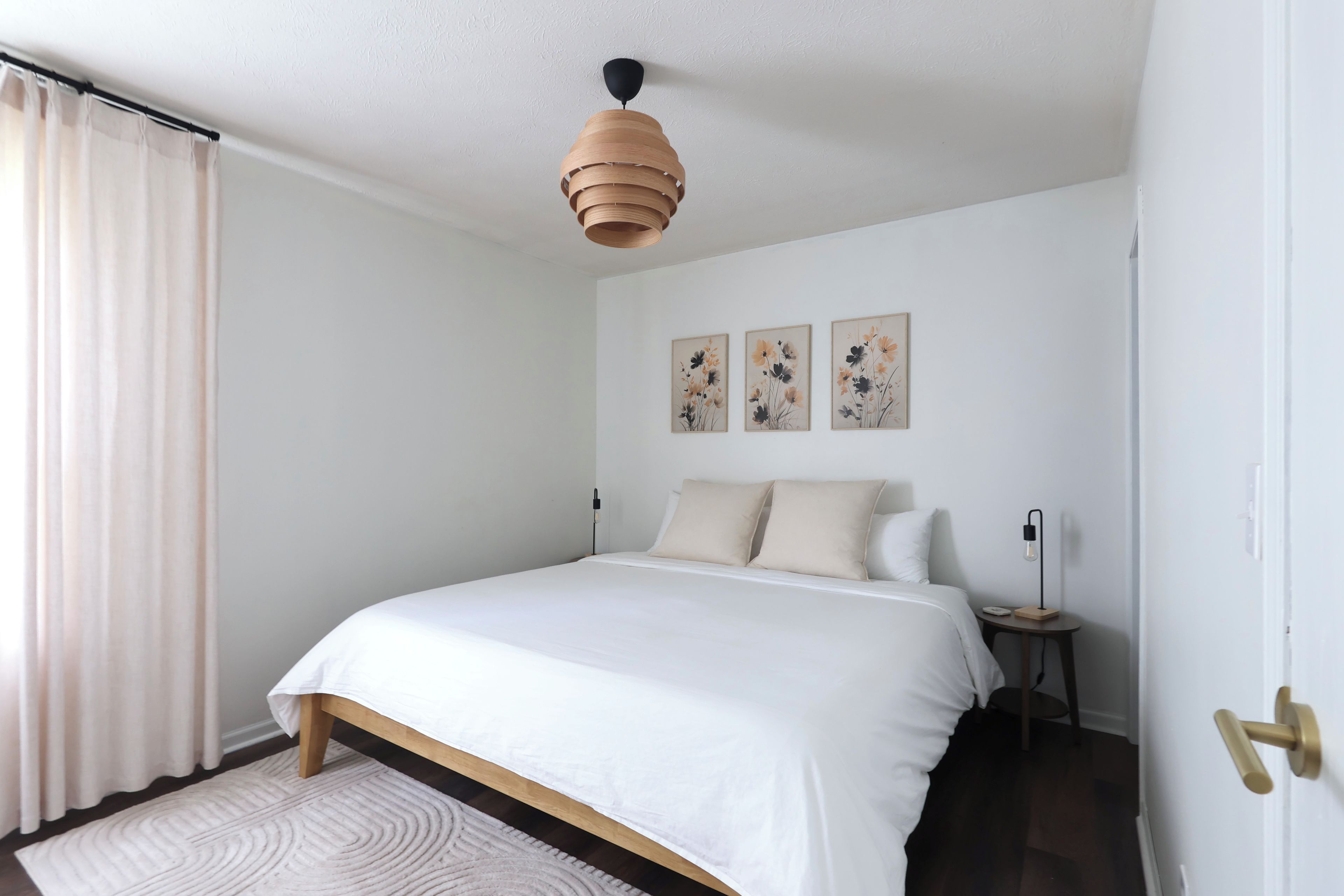 A bedroom with a bed, a bedside table, a lamp, and a door.