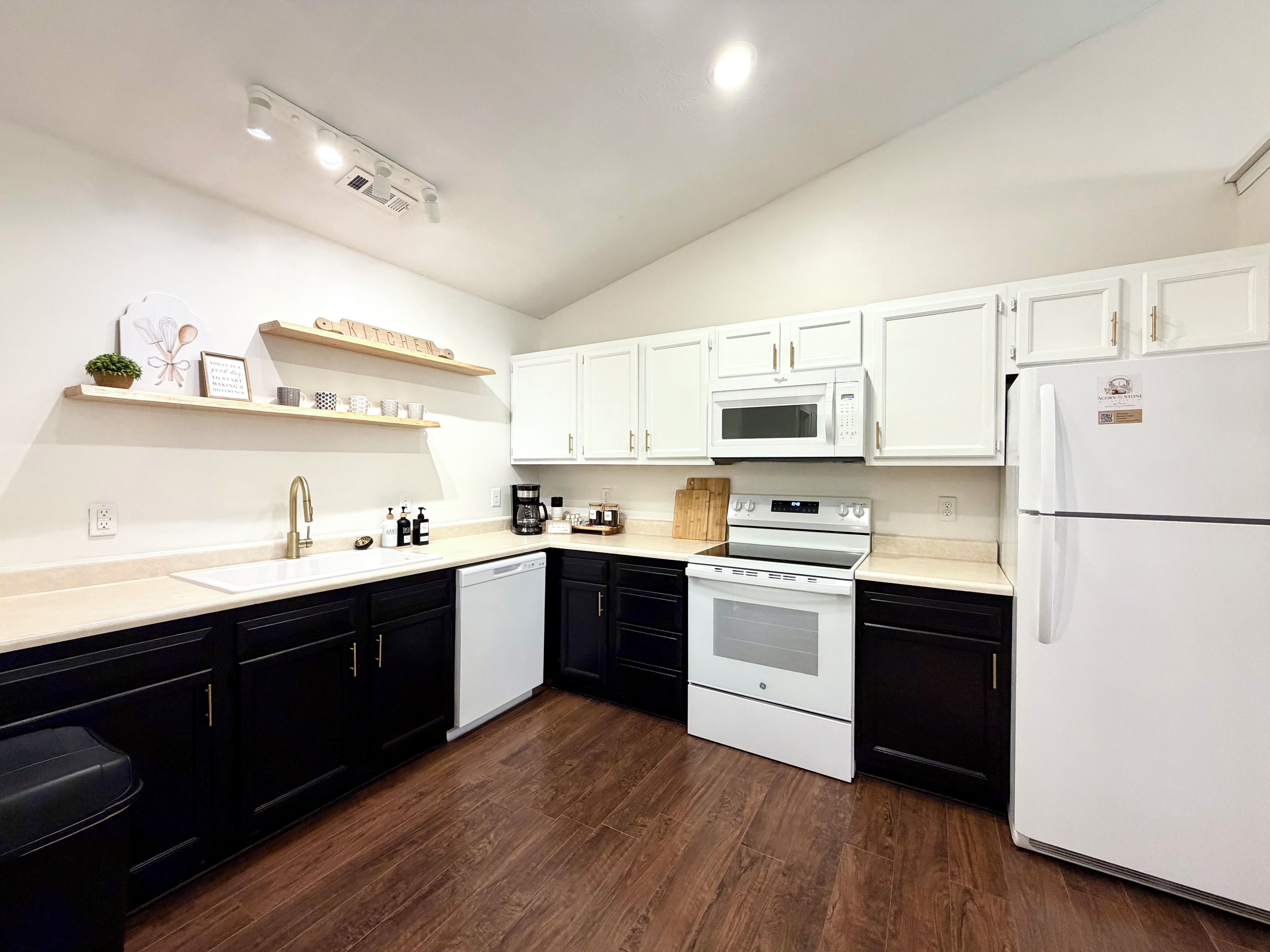 Una cocina moderna con armarios blancos, un lavavajillas negro y un refrigerador blanco.