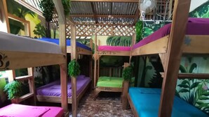 Quarto com beliches, ventoinha e painel tropical.