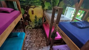 Quarto com beliches, um mural e piso de azulejos.