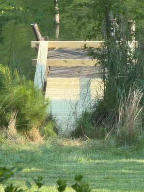 A wooden dock extending into a body of water, surrounded by grass and trees. - Our Lake Wylie, SC 4BR/2BA waterfront House, sleeps 6 max., pier & dock. (Clover)
