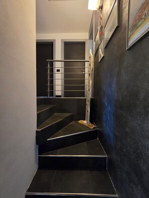 A staircase with a metal railing leading to a door, a wall with a textured finish, and a framed picture.