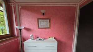 A room with a white dresser against a pink wall, a framed artwork above it, and a floor lamp to the left. - Chalet Soàndel Nature & Relax (Trentino-Alto Adige)