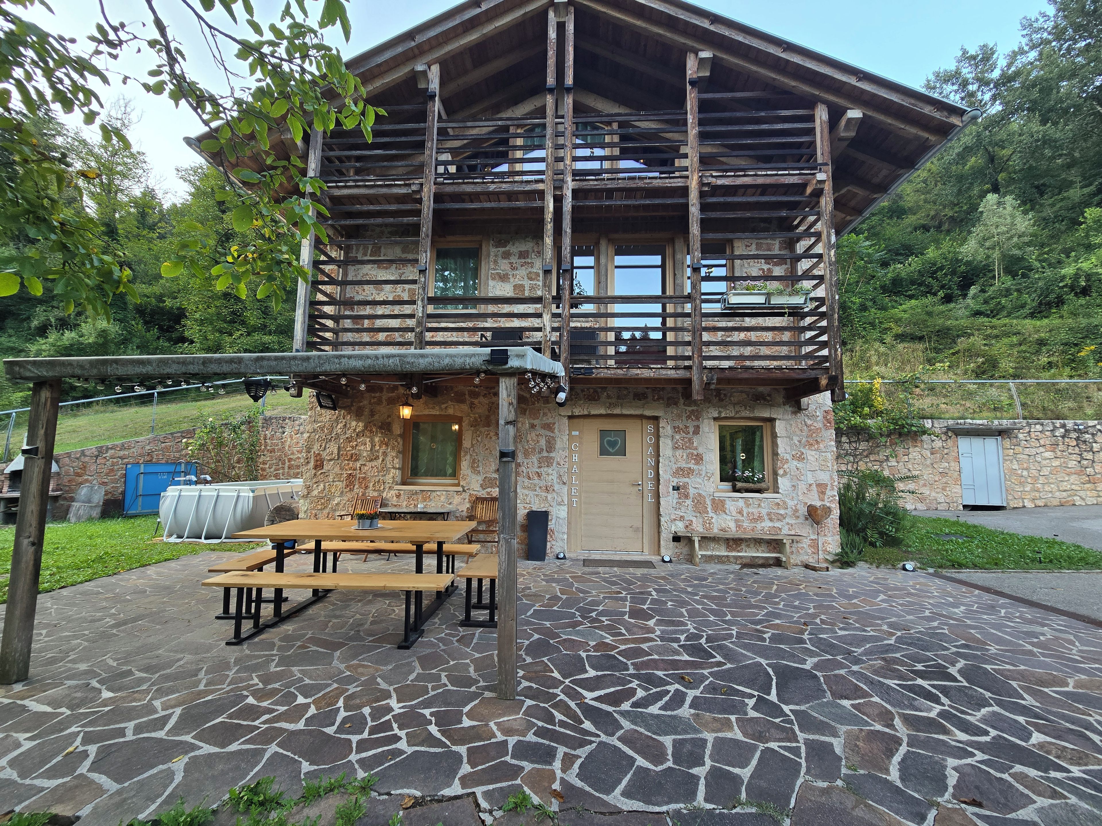 A stone building with a wooden deck, outdoor seating, and a stone patio.