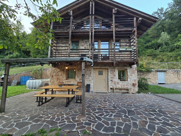 A stone building with a wooden deck, outdoor seating, and a stone patio.