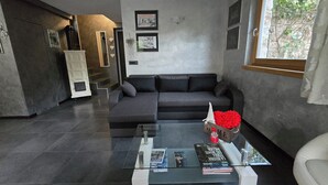 En moderne stue med en grå sofa, et glasbord og en pejs.