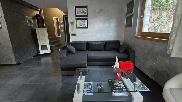 A modern living room with a grey sofa, a glass coffee table, and a fireplace. - Chalet Soàndel Nature & Relax (Trentino-Alto Adige)