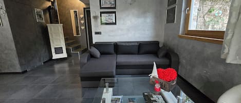 A modern living room with a grey sofa, a glass coffee table, and a fireplace.