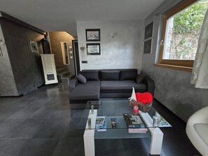 A modern living room with a grey sofa, a glass coffee table, and a fireplace. - Chalet Soàndel Nature & Relax (Trentino-Alto Adige)