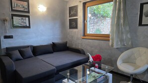 A modern living room with a grey sofa, a glass coffee table, a white armchair, and framed pictures on the wall. - Chalet Soàndel Nature & Relax (Trentino-Alto Adige)