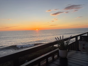 A sunset view from a balcony overlooking the ocean, with a railing and a potted plant. - Luxurious Oceanfront Condo w/ Endless views and Sunsets (San Diego)