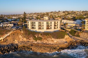 A coastal building with multiple balconies, situated on a rocky cliff overlooking the sea. - Luxurious Oceanfront Condo w/ Endless views and Sunsets (San Diego)