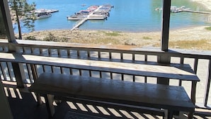 Zona salotto coperta con vista su un lago e barche ormeggiate.