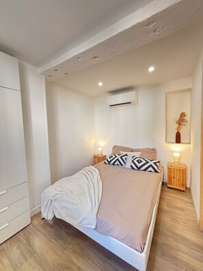 Ein Schlafzimmer mit einem Bett, Nachttischen, einer Klimaanlage und einem Kleiderschrank.