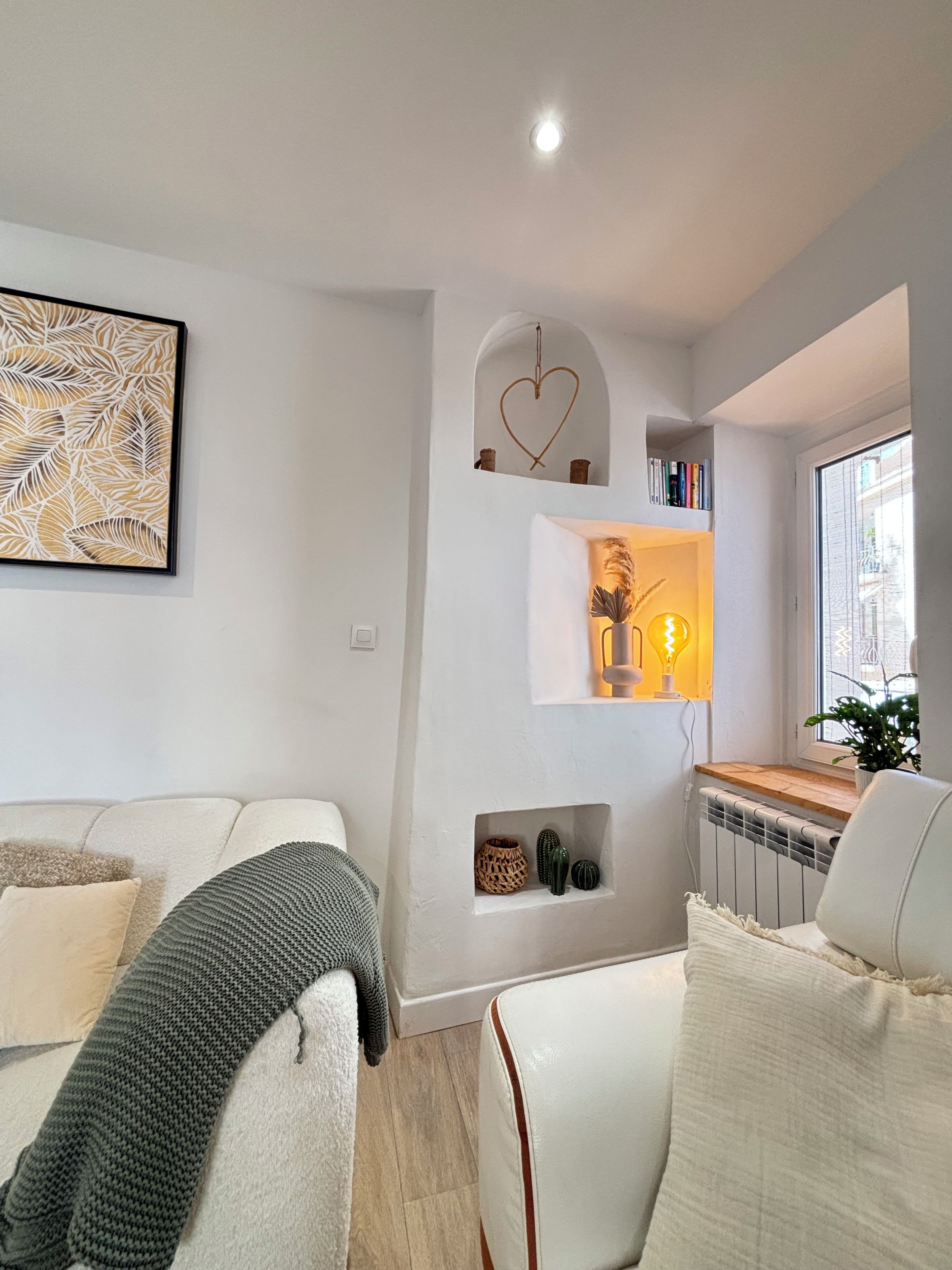A modern living room with a sofa, a coffee table, and a wall-mounted shelf with decorative items.