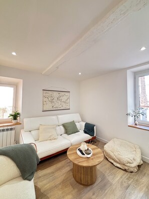 A modern living room with a white sofa, a round wooden coffee table, and a large window. - Spacious, ideal 3-bedroom apartment on the harbor, right in the heart of Sanary (Sanary-sur-Mer)