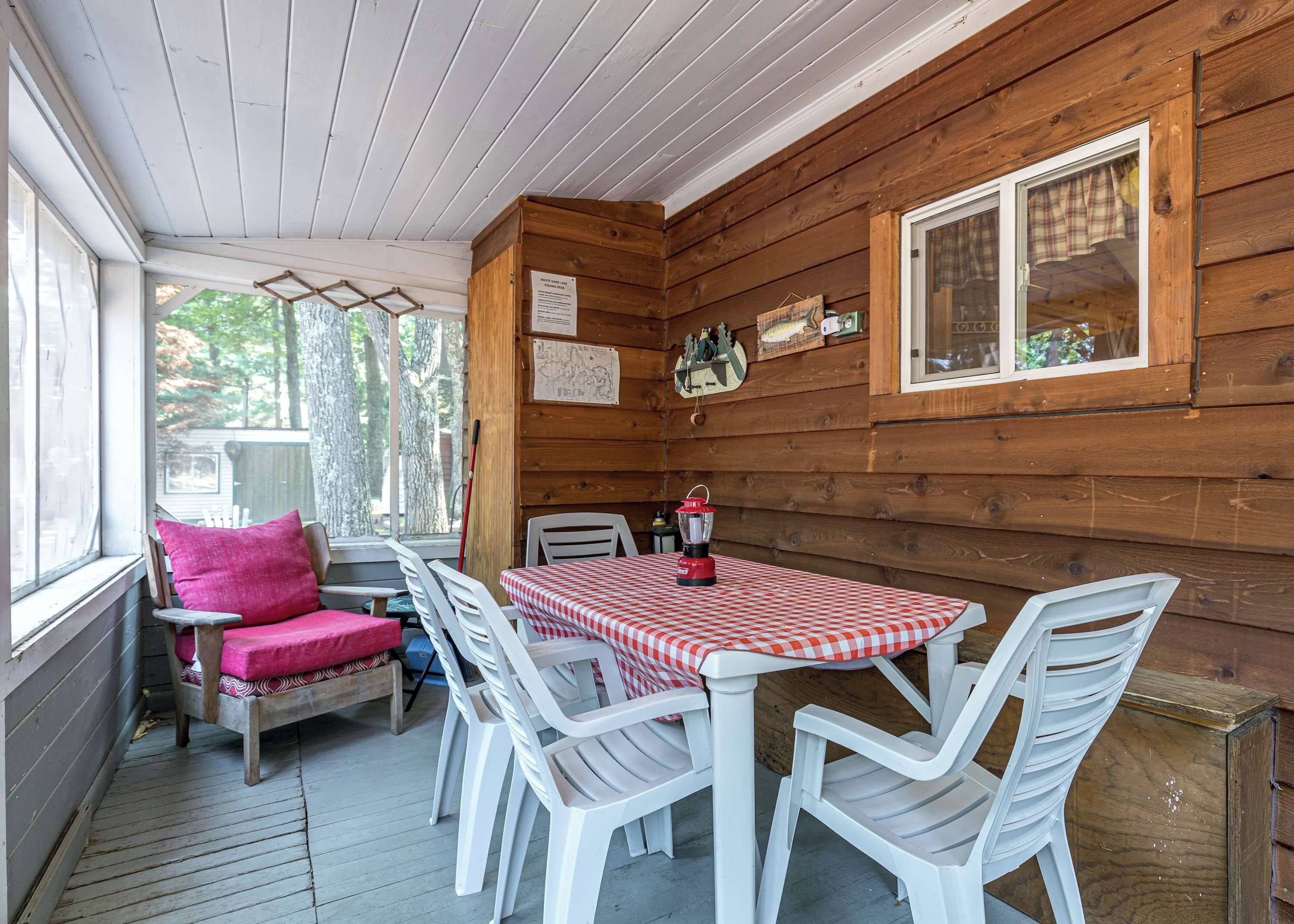 Une cabane en bois avec une table à manger dressée pour quatre personnes, entourée de chaises en plastique blanc.