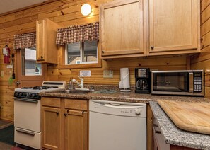 A kitchen with wooden cabinets, a stove, a microwave, and a coffee maker.
