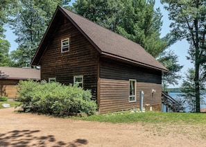 A wooden cabin with a pitched roof, surrounded by trees and a body of water. - Maplewood Cabin, Resort, Lake, Beach, Kayaks & More (Lac du Flambeau)