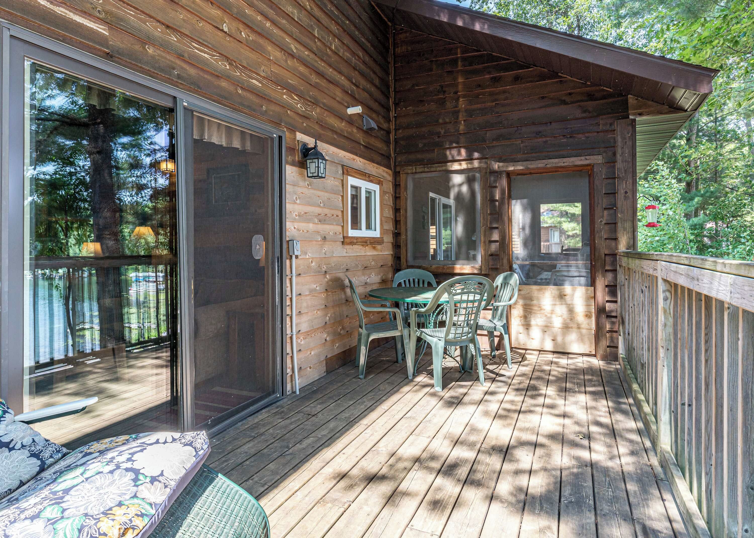 Une terrasse en bois avec une table et des chaises, une porte-fenêtre coulissante et une vue sur l’extérieur.