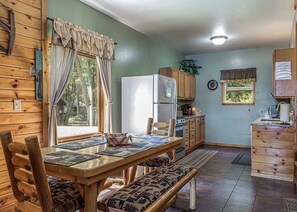 A wooden cabin interior with a dining table, chairs, a refrigerator, a stove, and a sink. - Maplewood Cabin, Resort, Lake, Beach, Kayaks & More (Lac du Flambeau)