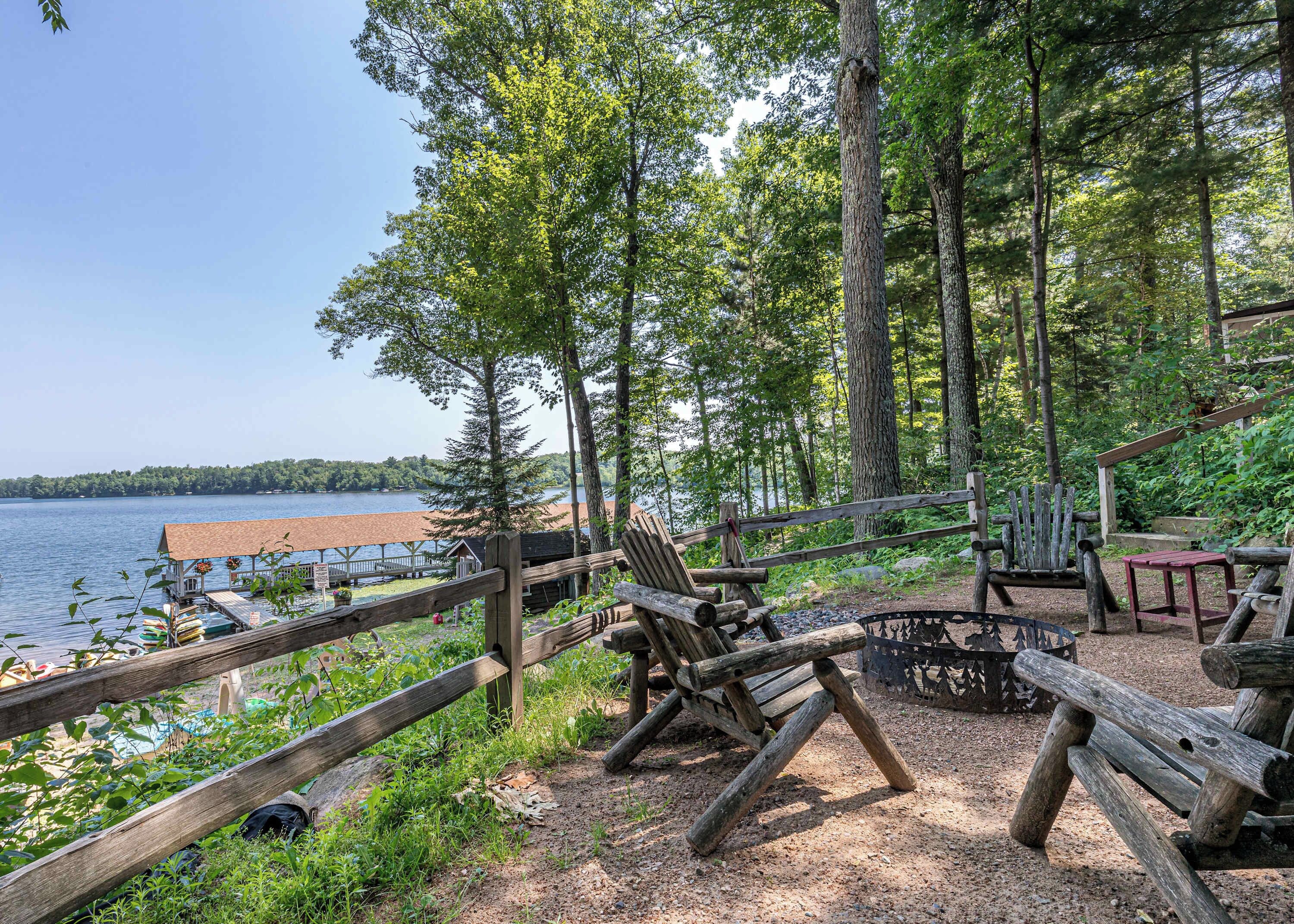 A rustic outdoor seating area with wooden furniture and a view of a lake.