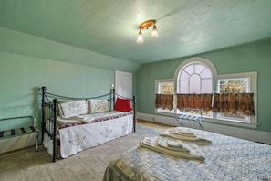 A room with a bed, a window with curtains, and a ceiling light fixture.