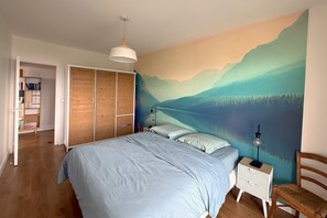 A bedroom with a bed, bedside lamps, a nightstand, a chair, a wardrobe, and a bookshelf.