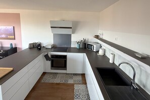 Una cocina compacta con horno empotrado, microondas y una pequeña zona de encimera.