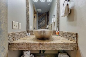 A bathroom with a large central sink, wooden countertop, and a mirror reflecting the room. - The Pirate Ship Chalet (Fish Haven)