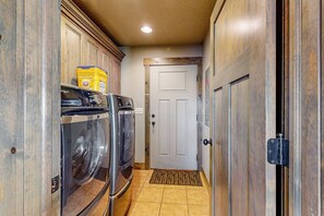 A narrow hallway with wooden cabinets, a white door, and a doormat. - The Pirate Ship Chalet (Fish Haven)