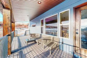 A wooden deck with outdoor furniture, large windows, and a view of a snowy landscape. - The Pirate Ship Chalet (Fish Haven)