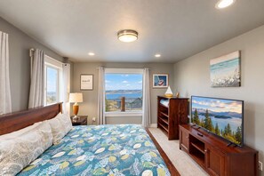 A hotel room with a large bed, a television, a window with a view, and a painting on the wall. - Serenity w/ Ideal Beach Access! (Garden City)