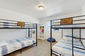 A room with bunk beds, a ceiling light, a shelf with items, and a window with blinds. - Flamingo Hideaway - with Indoor Sauna (Garden City)