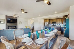 A modern living room with a dining area, kitchen, and a staircase. - Flamingo Hideaway - with Indoor Sauna (Garden City)