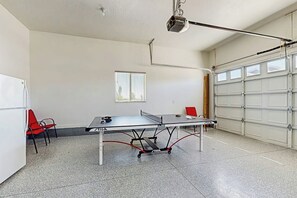 A ping pong table in a garage with a ceiling-mounted projector. - Flamingo Hideaway - with Indoor Sauna (Garden City)
