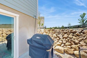 Eine Terrassenfläche mit Grill und einer Glastür, die zu einem Raum führt.