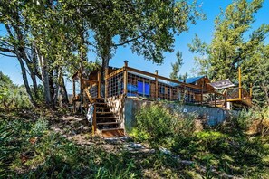 A cabin with a staircase leading to a wooden deck, surrounded by trees. - On the Waterfront - Lakefront with Mountain Views (Fish Haven)