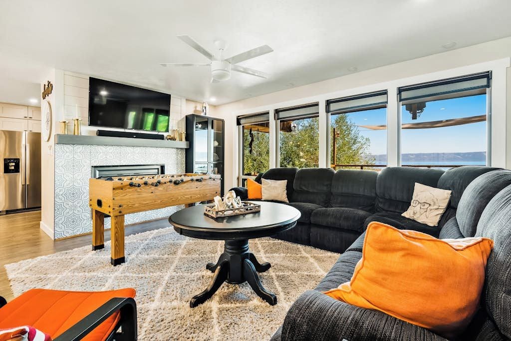 A modern living room with a foosball table, a comfortable sofa, and a flat-screen TV.
