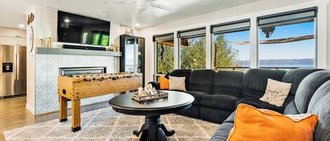 A modern living room with a foosball table, a comfortable sofa, and a flat-screen TV.